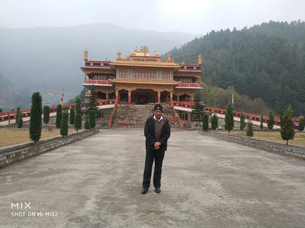 Paved monastery courtyard against the misty Dirang valley pine forest backdrop