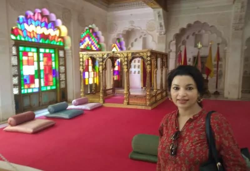Colorful stained-glass windows and red-carpeted palace hall in Jodhpur
