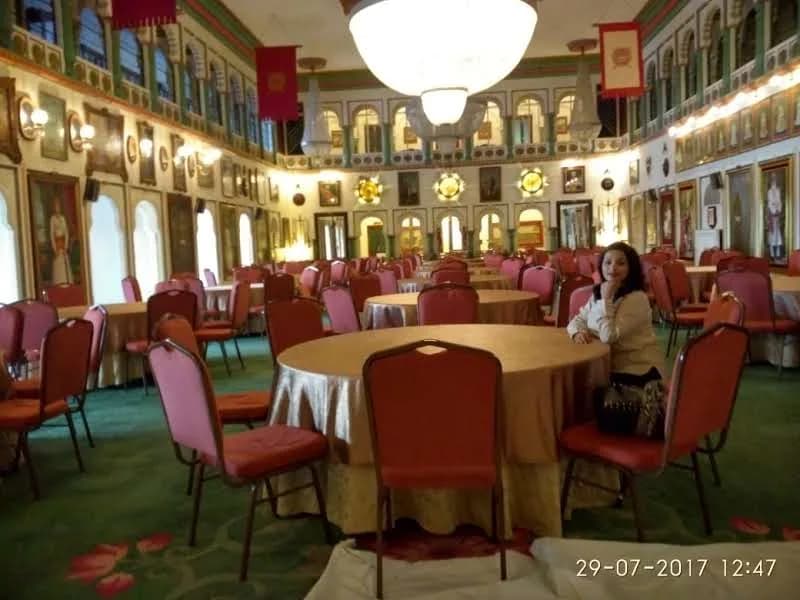 Grand interior of Durbar Hall at Fateh Prakash Palace showing crystal chandeliers, royal portraits, and red velvet seating