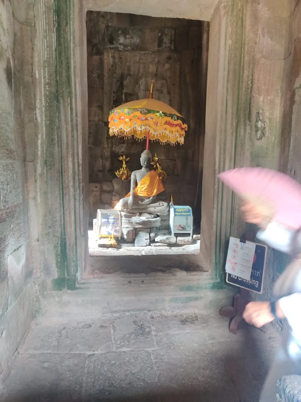 Buddha statue with a yellow umbrella inside Bayon temple