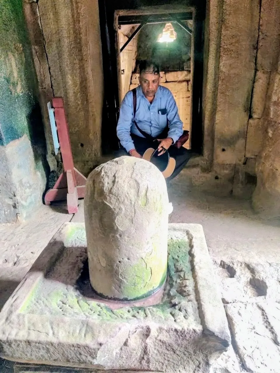 Man sitting behind a Shiva linga inside Bayon temple