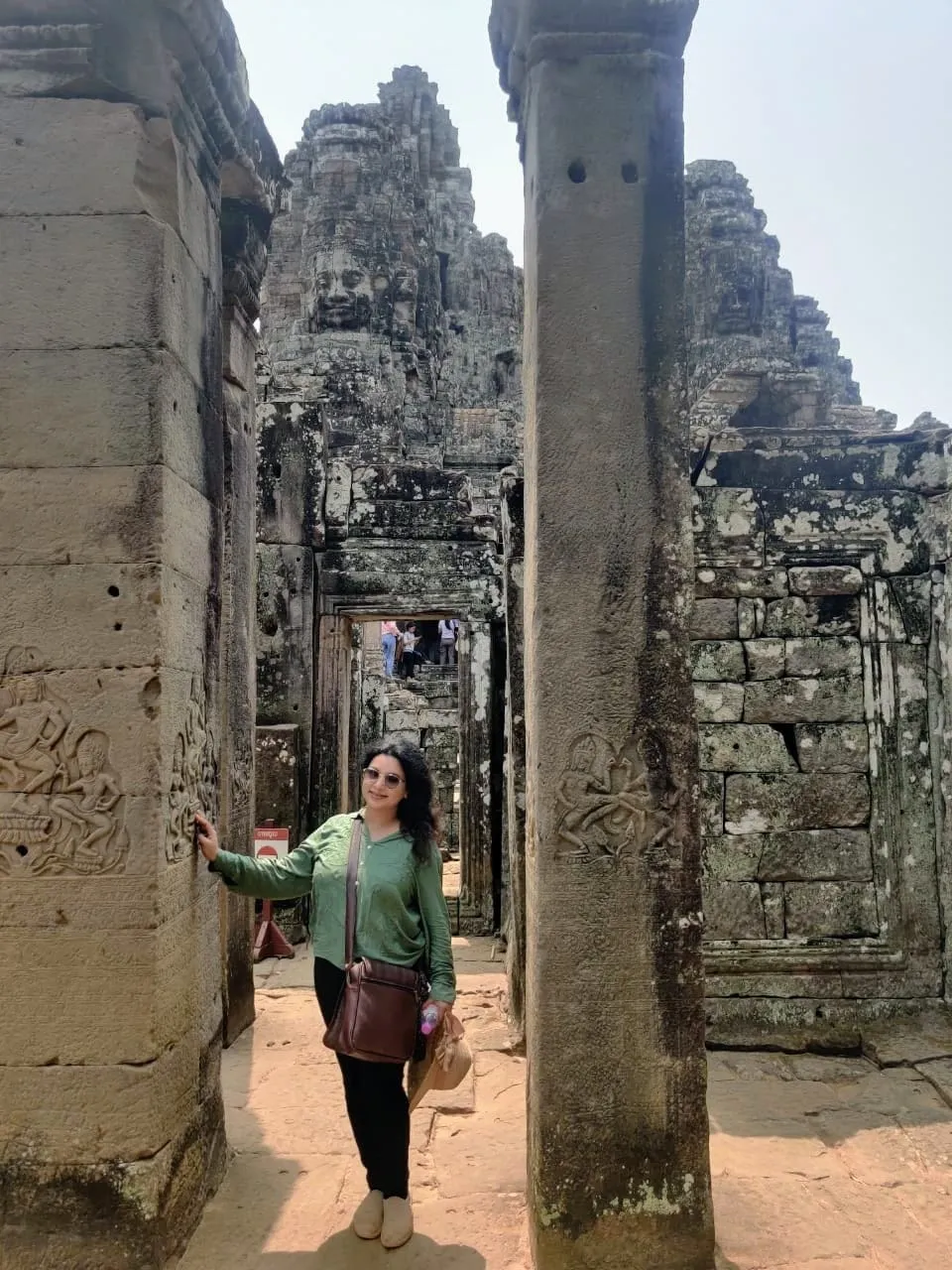 Woman standing between carved stone pillars at Bayon temple