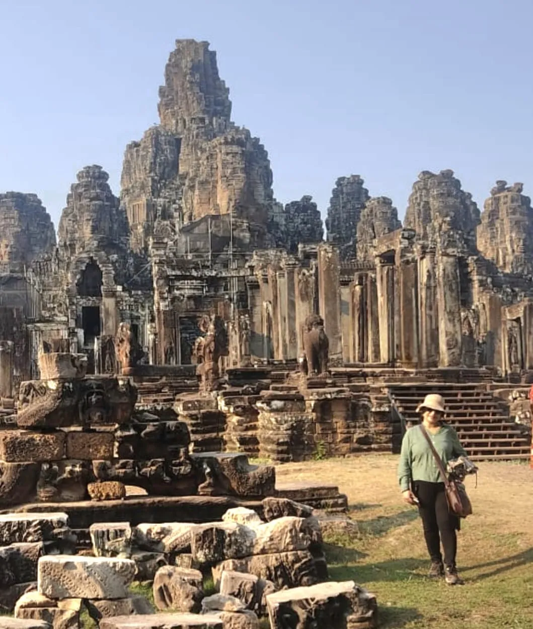 Woman standing in front of the impressive Bayon temple ruins with towering stone faces