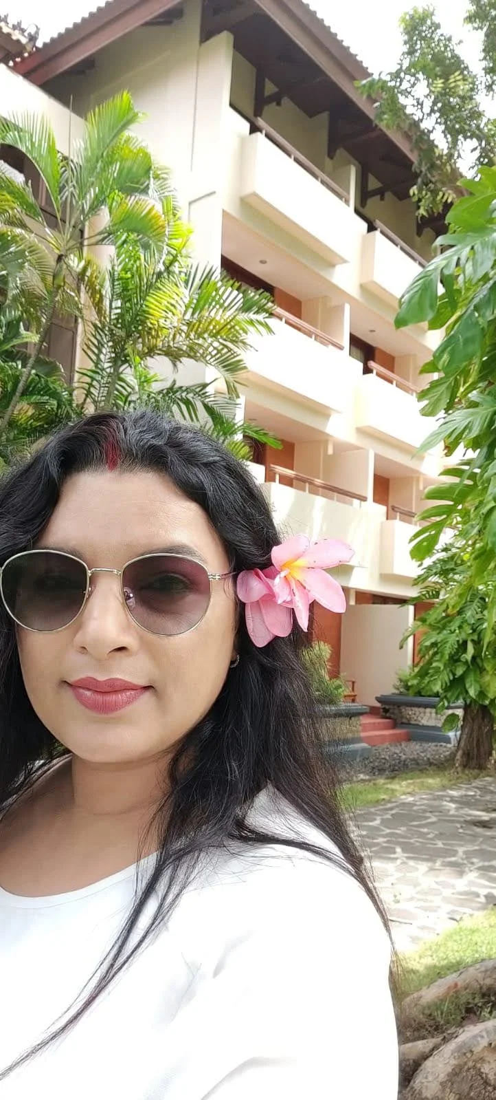 Archana with pink frangipani flower in Bali resort surrounded by tropical gardens