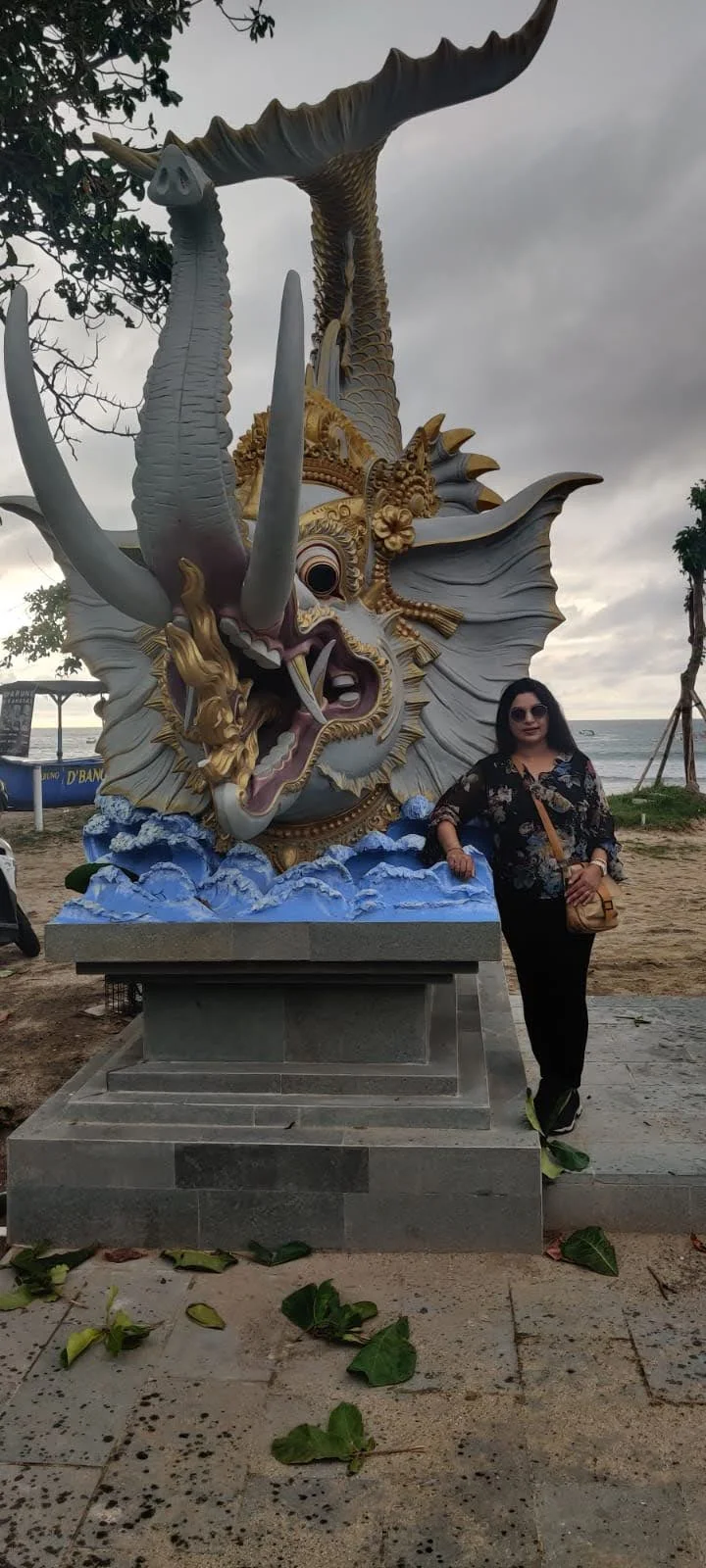Archana standing beside the ornate Gajah Mina statue combining elephant head and fish body by the sea in Bali