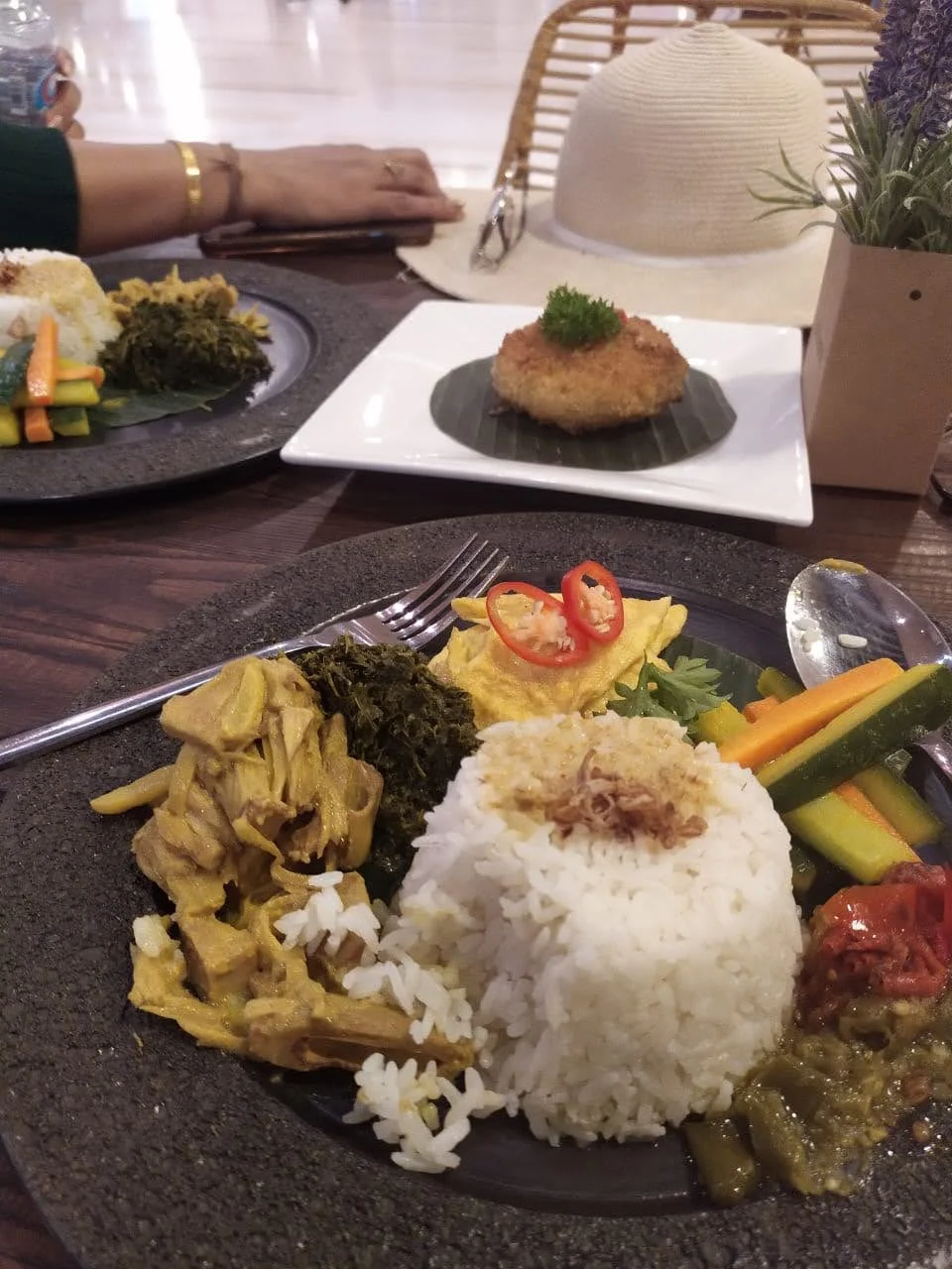 Authentic Nasi Padang rice platter featuring steamed rice, gulai nangka, cassava leaves, sambals, and omelet