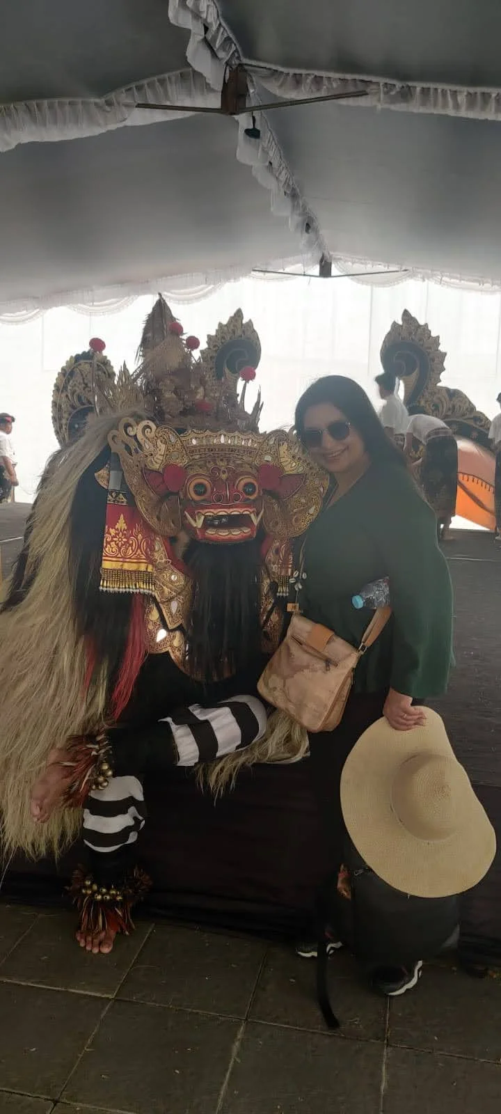 Archana standing beside the masked Barong / mythological dancer in ornate costume