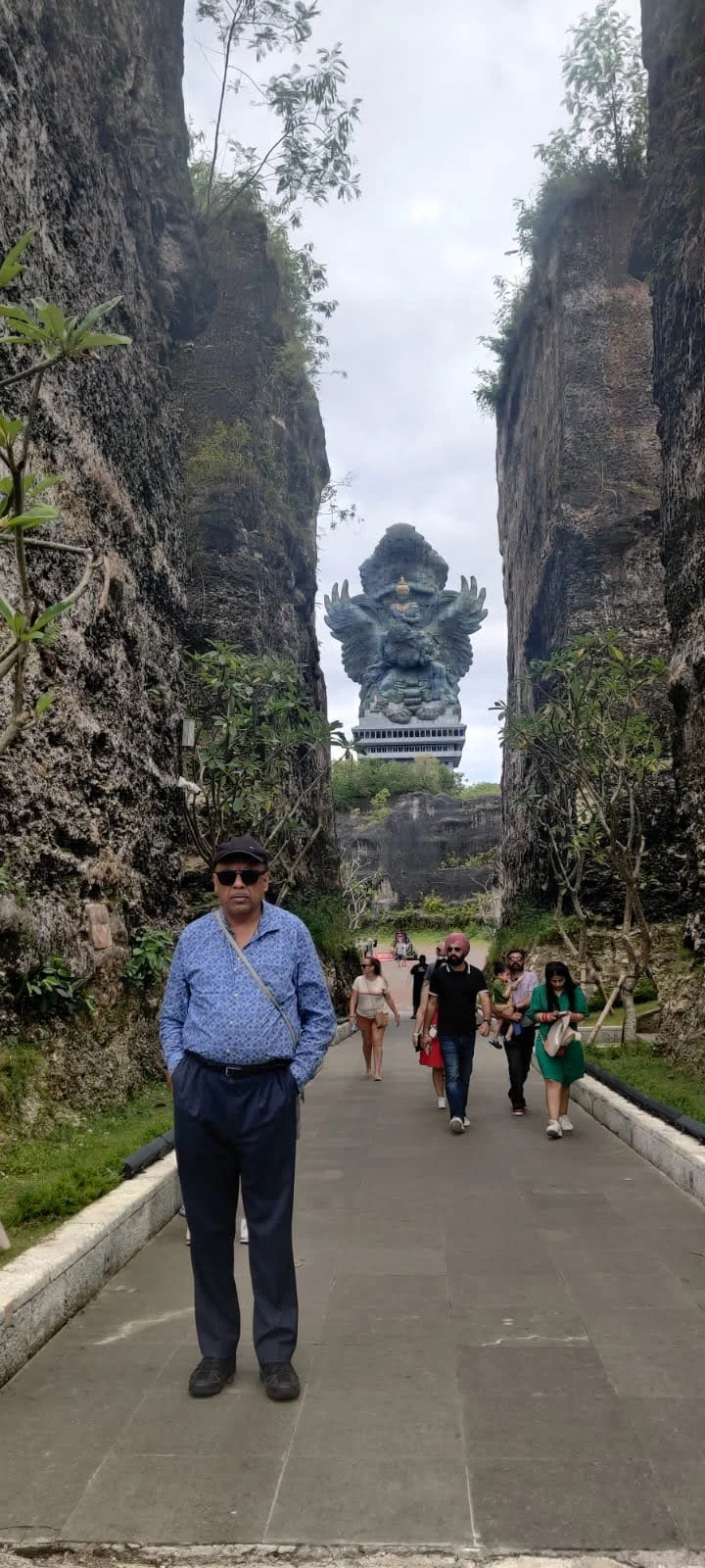 Traveler walking through the limestone canyon corridor with GWK statue centered