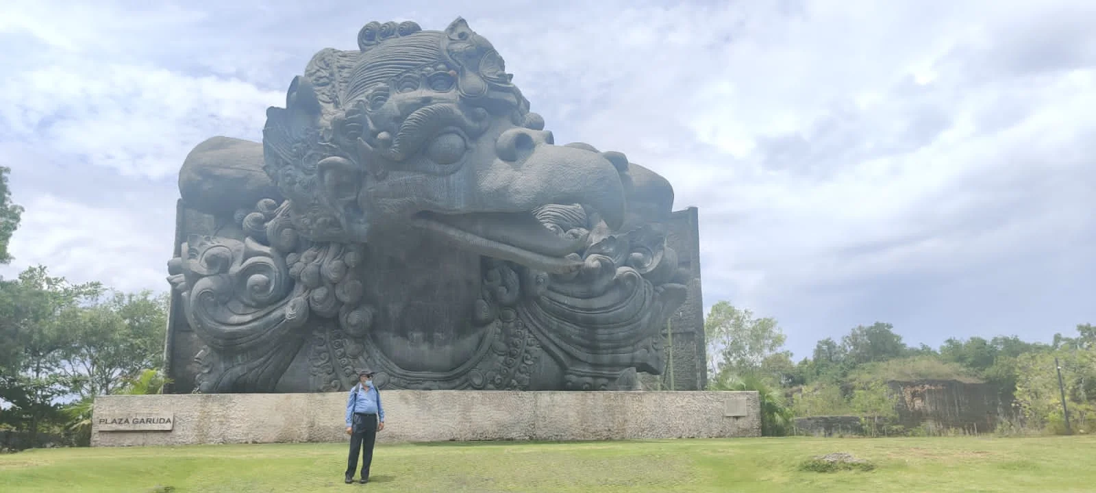 Traveler in Plaza Garuda before the massive carved head and shoulders of Garuda