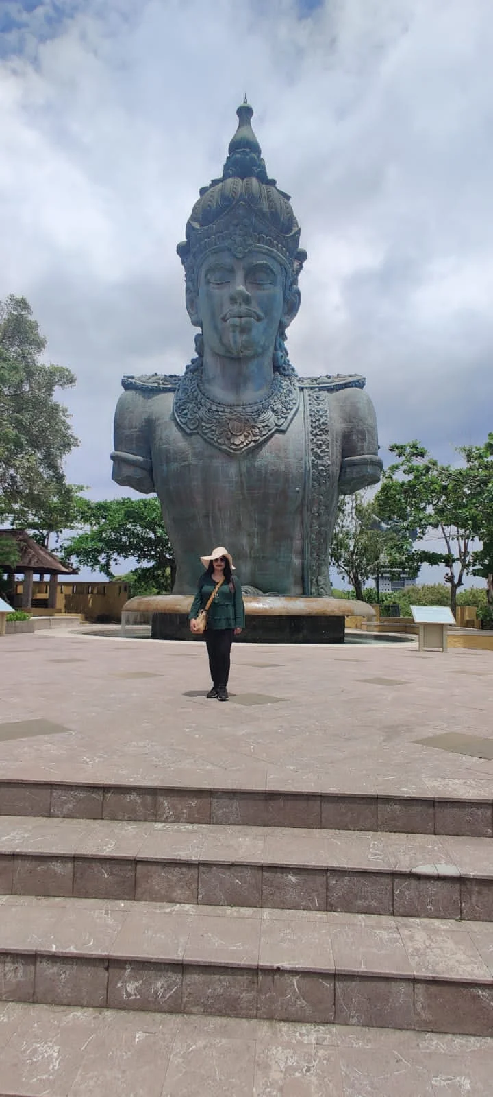 Archana standing in Plaza Wisnu before the massive colossal bronze bust of Lord Vishnu
