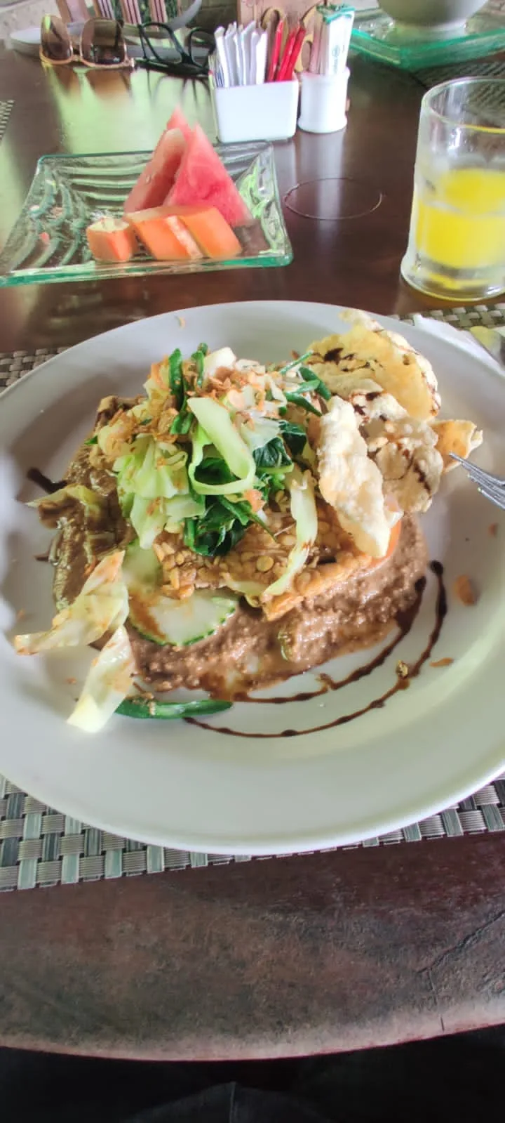 Traditional Indonesian Gado-gado salad plate with vegetables, tempeh, tofu, savory peanut sauce, and crispy kerupuk crackers