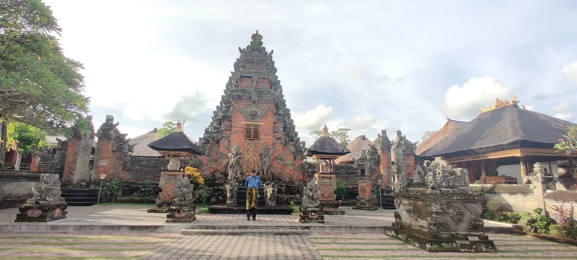 Traveler standing before the towering central Kori Agung stepped tower gateway of Batuan Temple