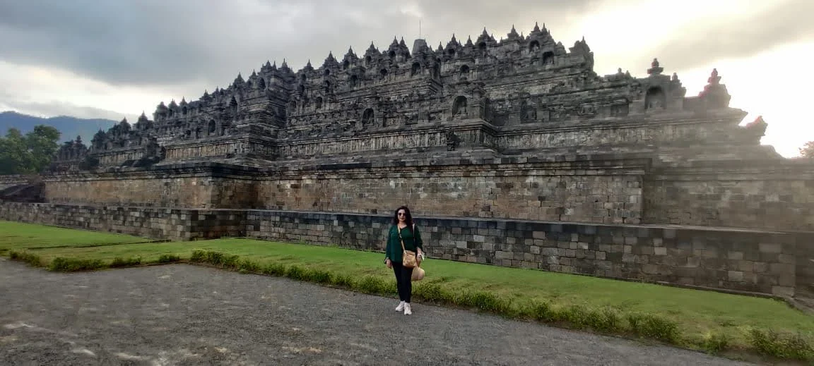 Traveler standing before the massive lower andesite stone terraces of Borobudur
