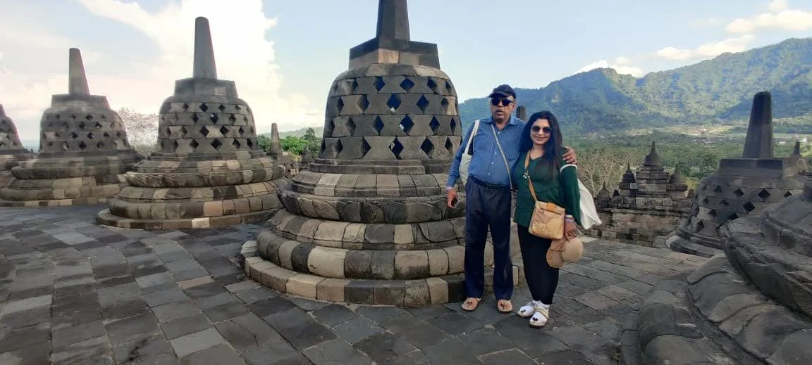 Couple on the upper circular terrace between bell-shaped lattice stupas under the open Javanese sky