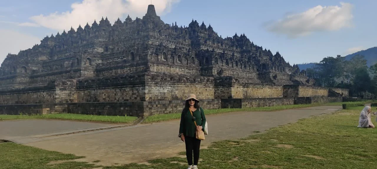 Panoramic view of Borobudur temple mountain rising against morning mist in Central Java with traveler centered