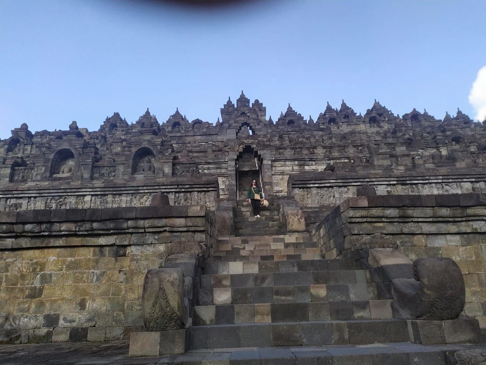 Traveler standing inside the monumental stone Kala portal gateway leading upward into the sacred galleries