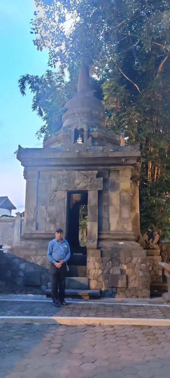 Traveler standing before stone candi crowned with stupa nestled beneath lush tropical trees at Mendut
