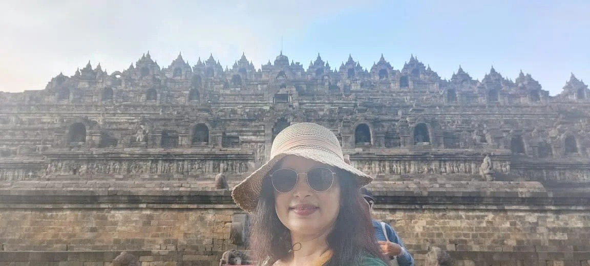 Traveler in sunhat close-up portrait before the majestic dark andesite tiers of Borobudur