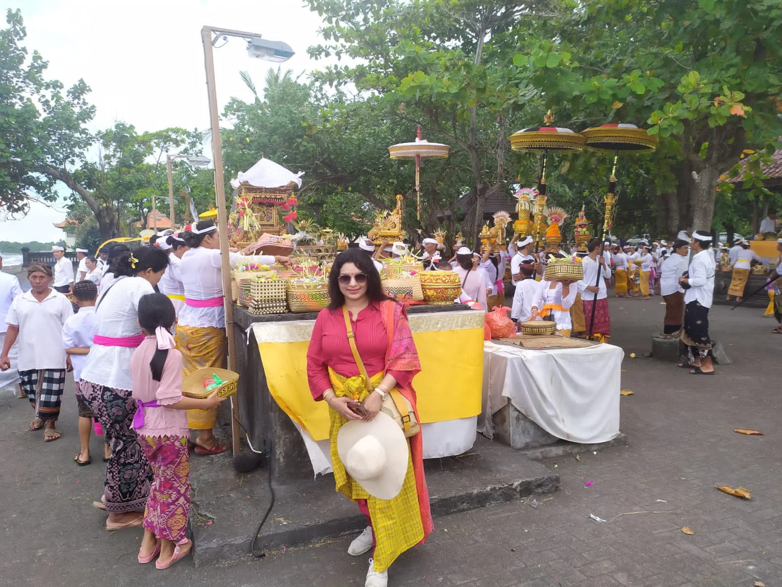 Lady traveler amidst the vibrant gathering of Balinese families in ceremonial white and yellow attire