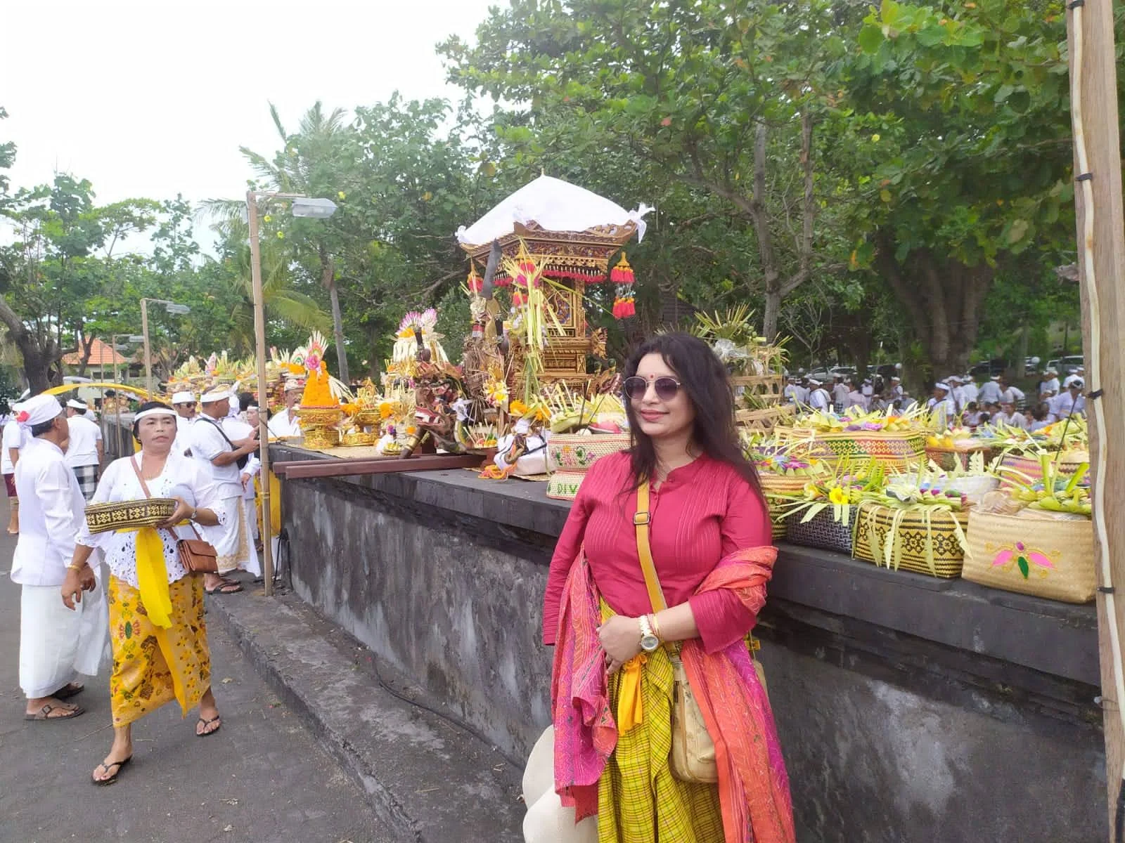 Lady traveler standing beside the ceremonial Odalan offering platform filled with woven bamboo creations