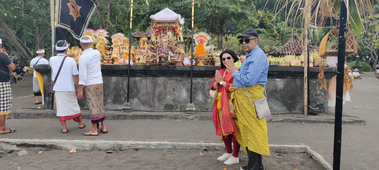 Both travelers in namaste posture before the Odalan temple offering altar and ceremonial palanquin