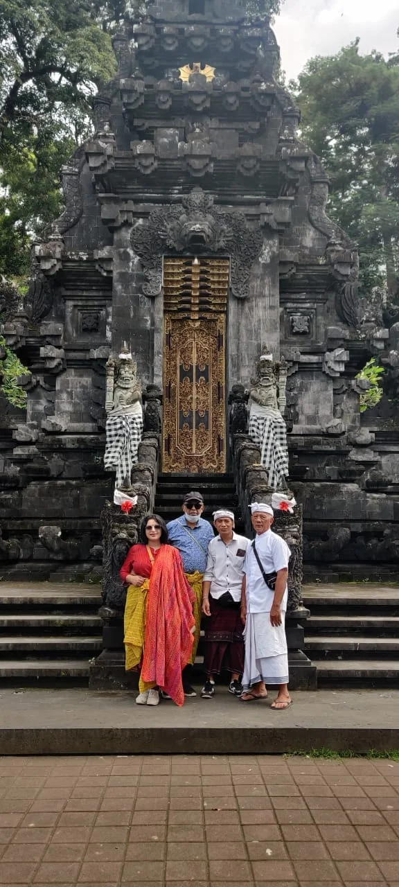 Both travelers photographed with Balinese temple elders in front of the ornate Kori Agung tower gateway