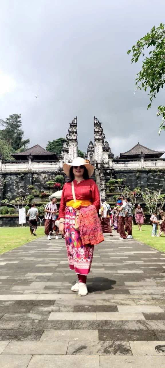 Lady traveler along the paved courtyard path with temple portals and mountain sky behind
