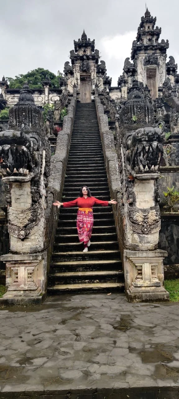 Lady traveler standing with open arms between the two soaring dragon staircases at Pura Lempuyang