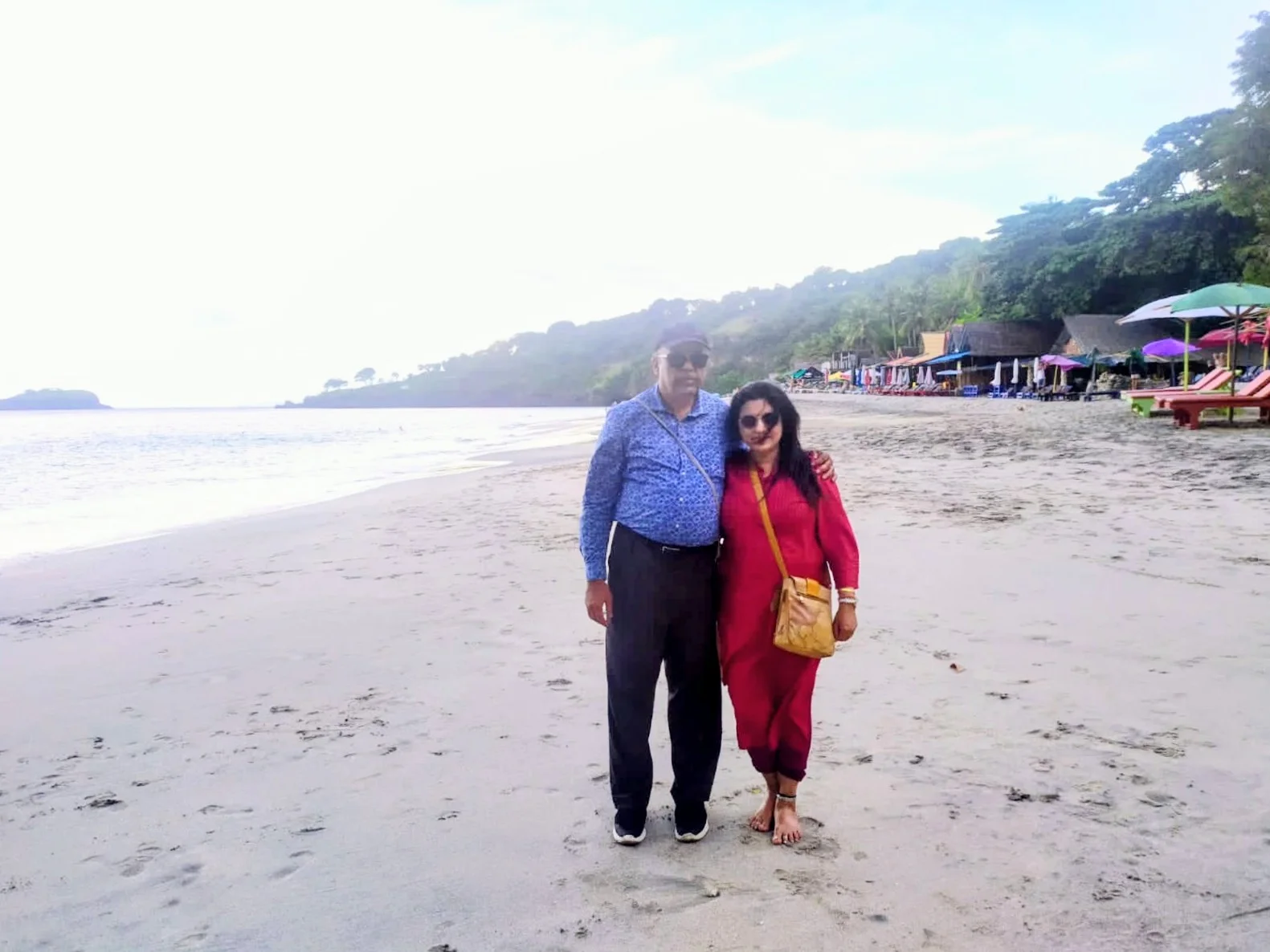 Both travelers relaxing barefoot on the white sand and turquoise bay of Virgin Beach in East Bali