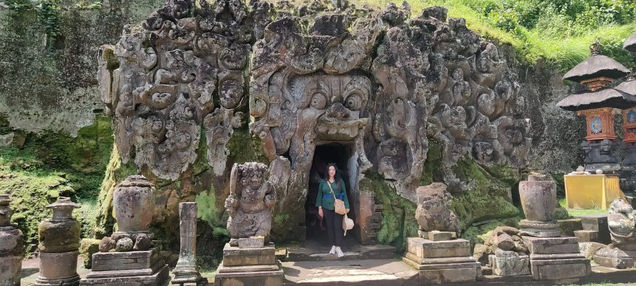 Traveler standing in the rock-carved demonic mouth entrance of Goa Gajah Elephant Cave