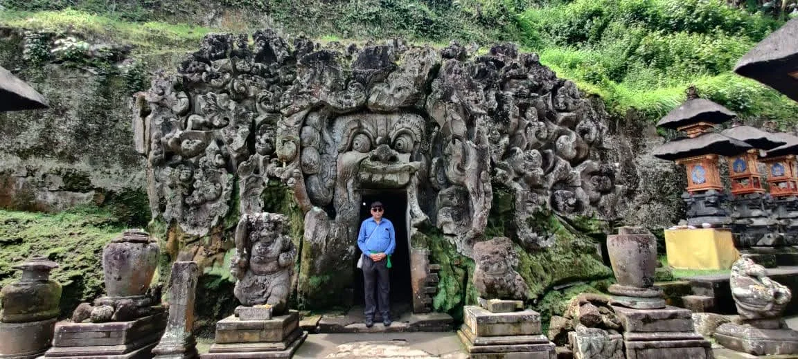 Traveler standing in the entrance of the rock-cut Goa Gajah Elephant Cave beneath the terrifying stone face