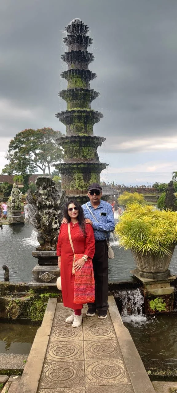 Both travelers standing on the lotus bridge directly before the iconic 11-tiered Nawa Sanga lotus fountain
