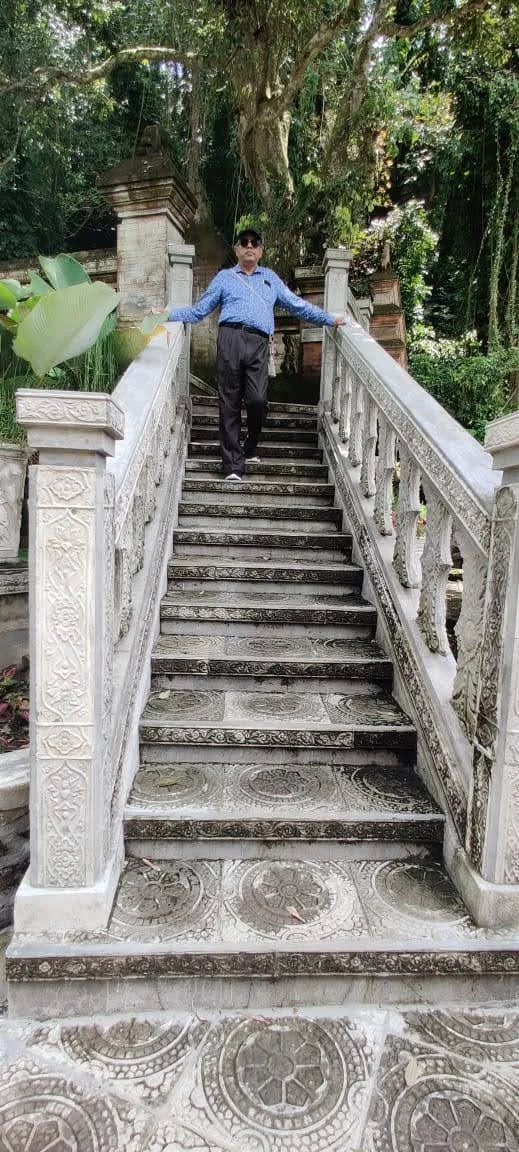 Traveler standing atop the carved Balinese stone balustrade staircase under shady trees
