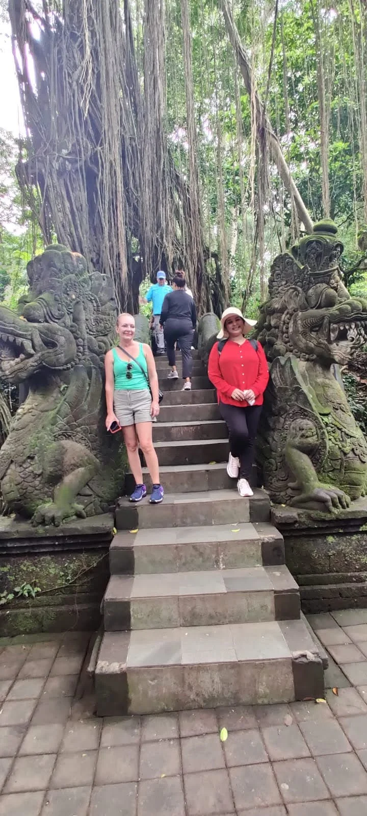 Lady traveler on the sacred stone staircase bordered by carved dragon balustrades and towering banyan trees