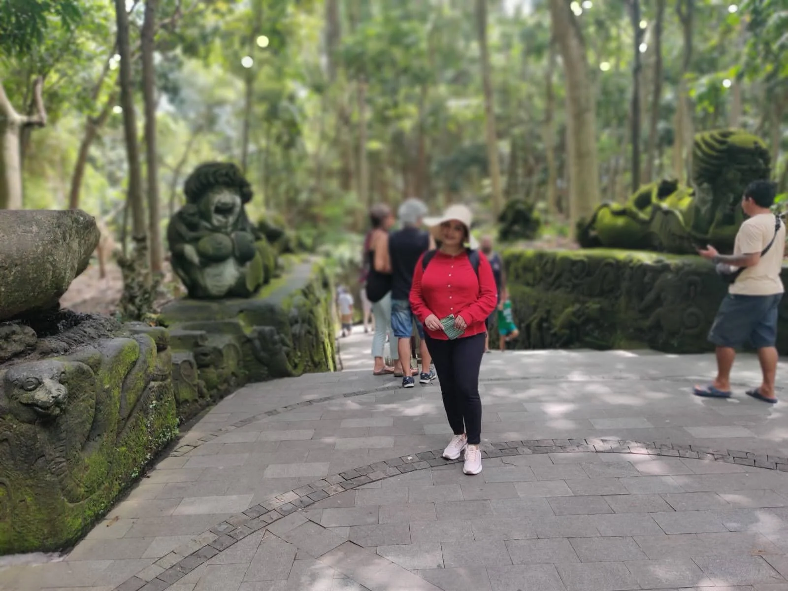 Lady traveler strolling the stone path flanked by ancient mossy mythological creature sculptures