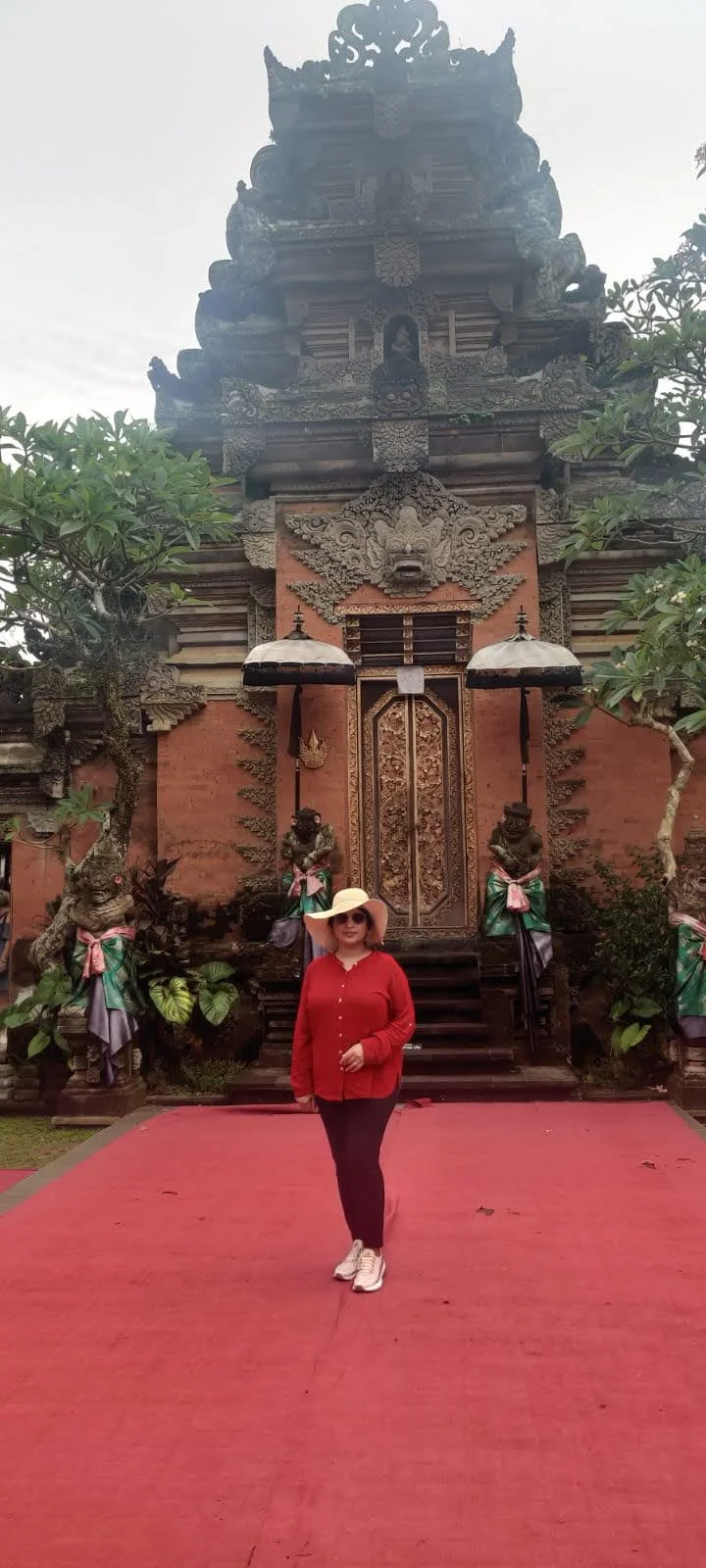 Lady traveler on the red carpeted dance courtyard framed by ceremonial Balinese Tedung umbrellas at Ubud Palace