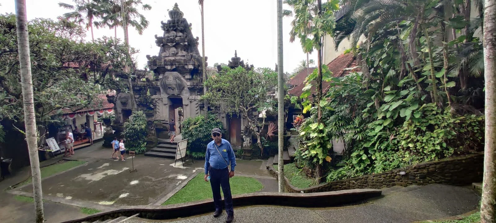 Elevated view of gentleman traveler in the historic courtyard of Ubud Palace before the towering stone Paduraksa gateway