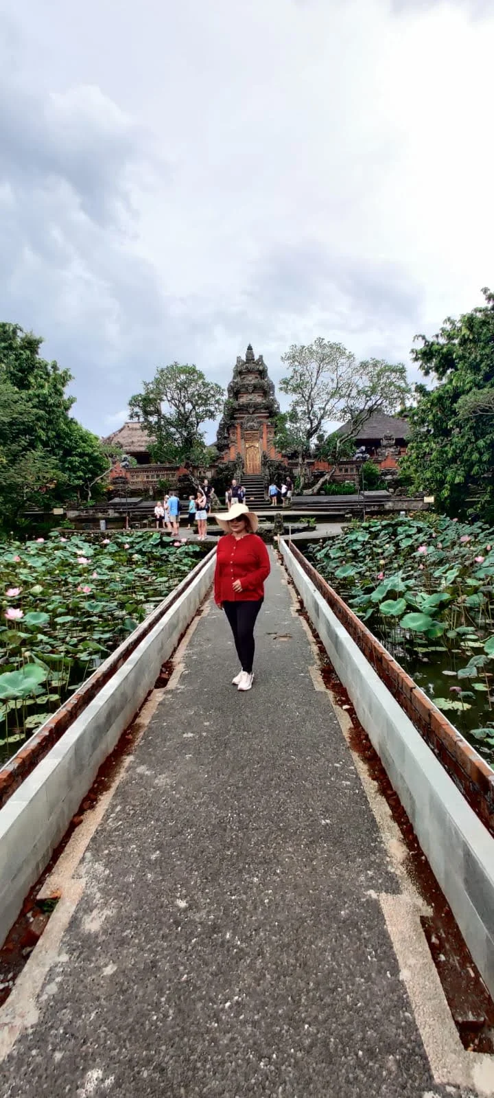 Traveler walking along the blooming lotus pond pathway at Pura Taman Saraswati in Ubud