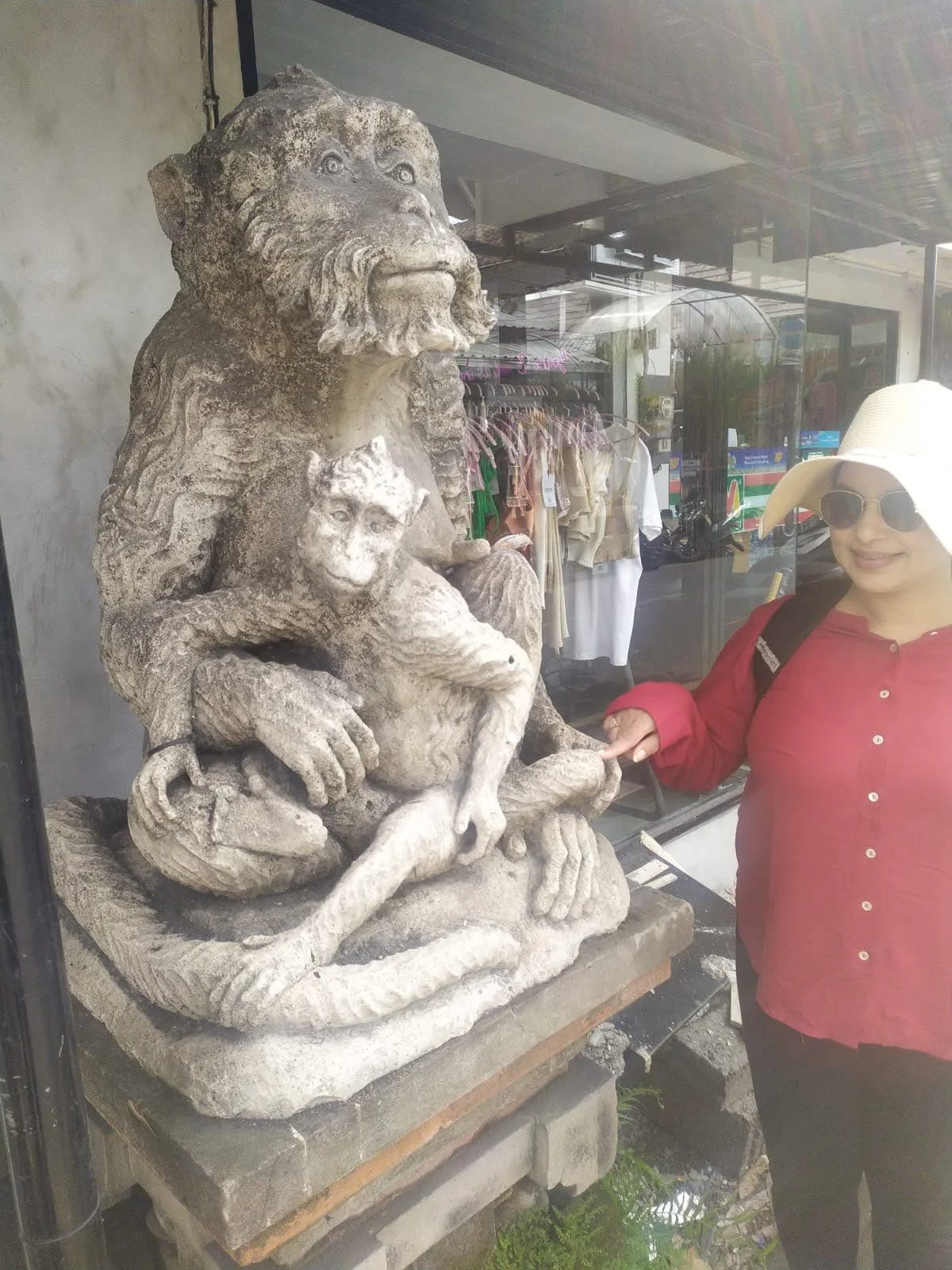 Lady traveler beside the iconic carved stone statue of a mother monkey and baby at the entrance to Ubud town