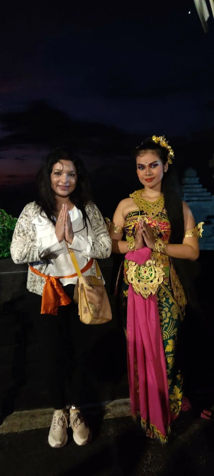 Lady traveler standing with the classical dancer in Dewi Sita regalia after the performance