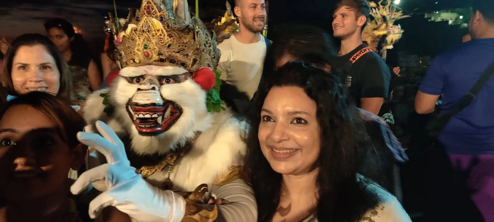 Lady traveler posing with the actor portraying Hanuman in full mask and white costume