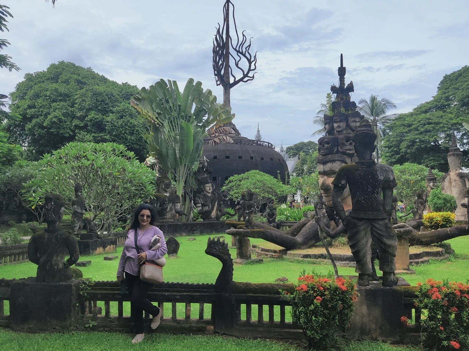Traveler wandering through the landscaped courtyard surrounded by dozens of imaginative concrete sculptures of devas, demons, and beasts