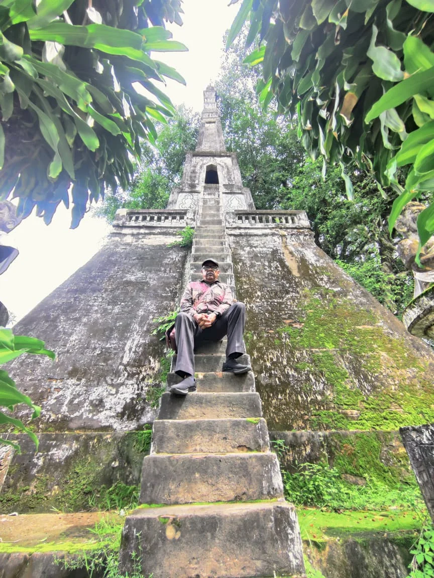 Traveler ascending the narrow concrete steps of the multi-tiered pyramid stupa representing cosmic Mount Meru