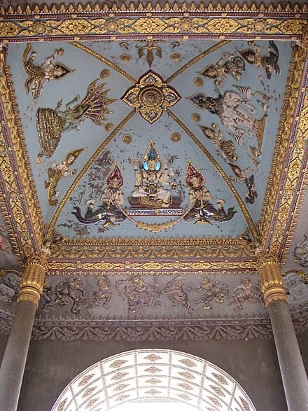 Intricate high-relief vaulted ceiling of Patuxai depicting Indra on Airavata elephant, Brahma, Vishnu, and celestial Kinnaris in gold and blue