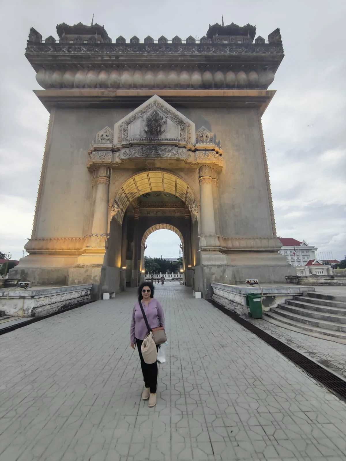 Traveler standing beneath the colossal triumphal archway of Patuxai Victory Gate along Lane Xang Avenue in Vientiane