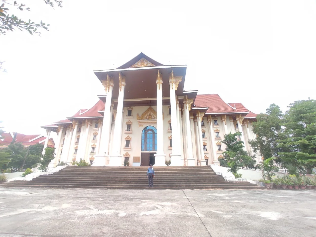 Male traveler standing at the grand portico steps of the Lao National Culture Hall in central Vientiane