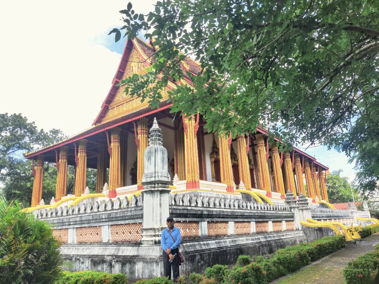 Male traveler standing on the stone terrace of Wat Ho Phra Keo admiring the classic Lan Xang architectural proportions
