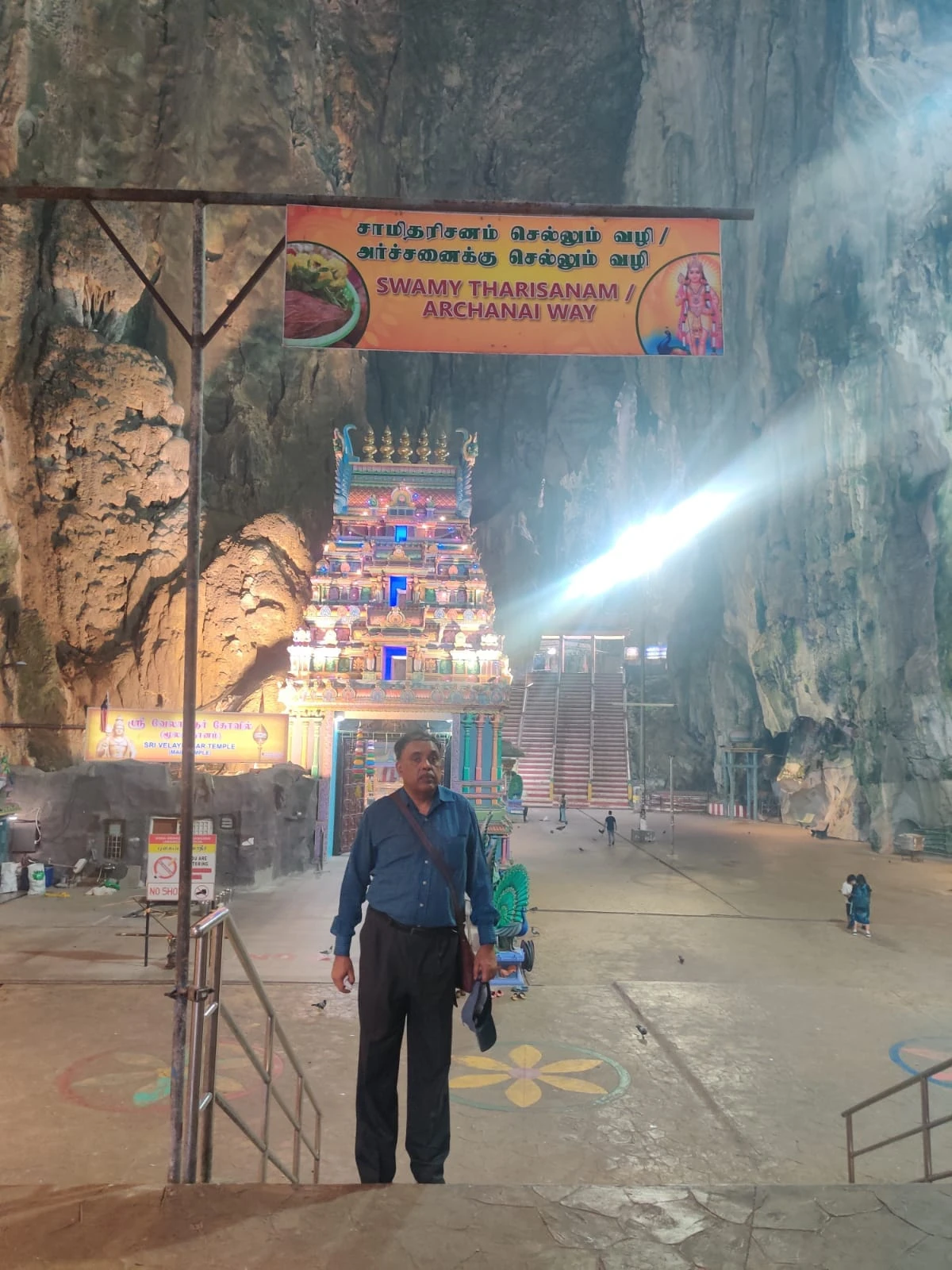 A dramatic beam of sunlight piercing through the limestone cavern skylight directly onto the Sri Velayuthar temple sanctum in Cathedral Cave
