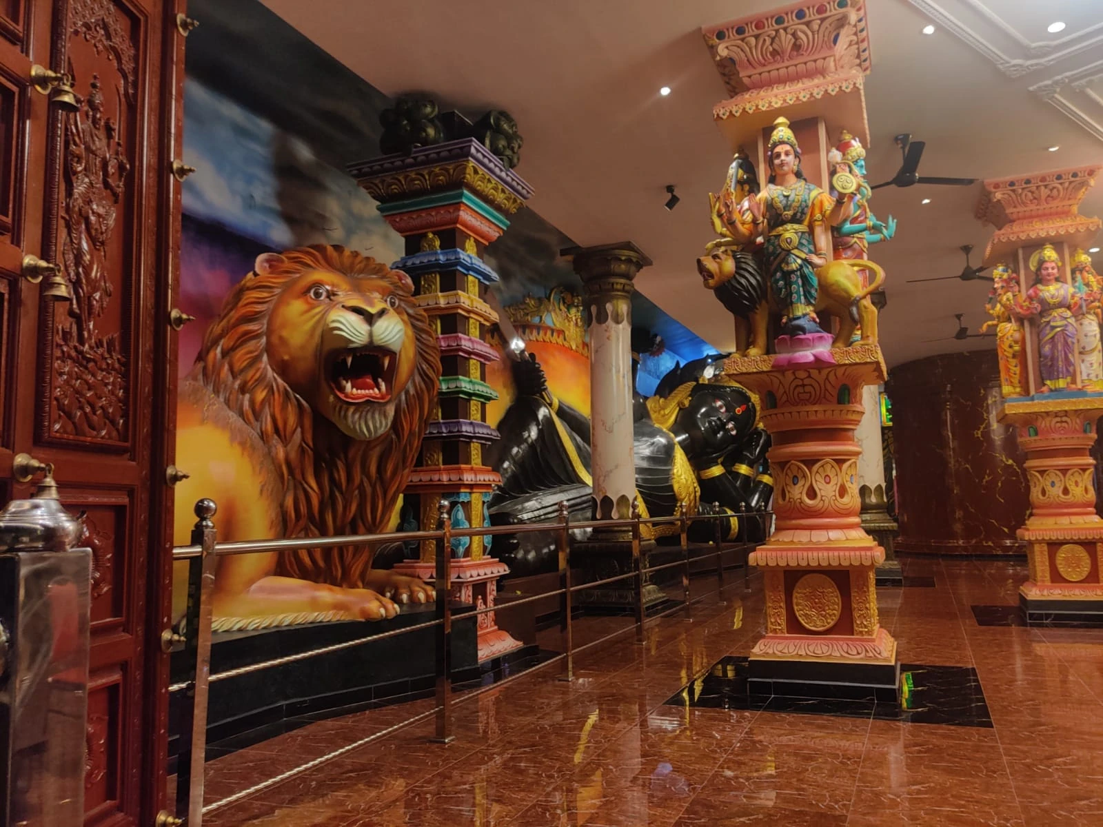 Vibrant polychrome sculpture of Goddess Durga riding her lion vahana amidst intricately sculpted cavern pillars in the Ramayana Cave