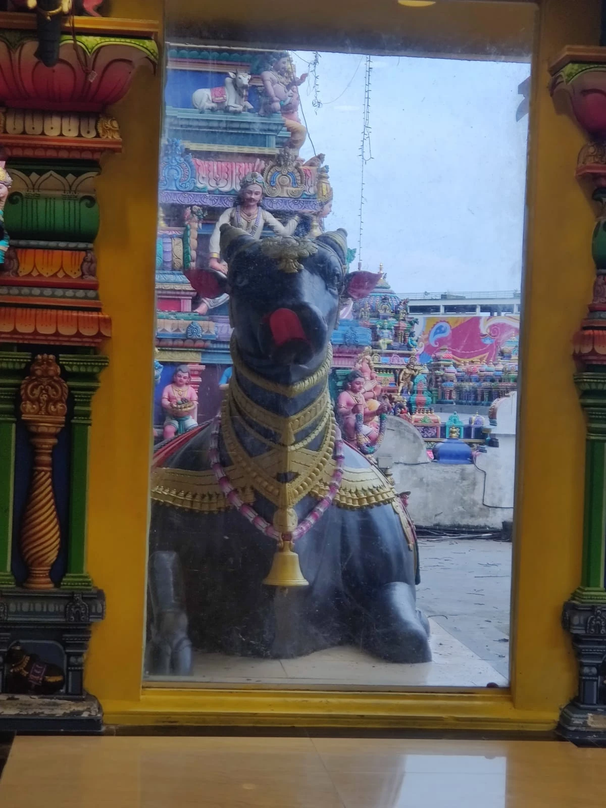 The sacred black Nandi bull shrine adorned with garlands, framed by the ornate multi-tiered temple gopuram behind